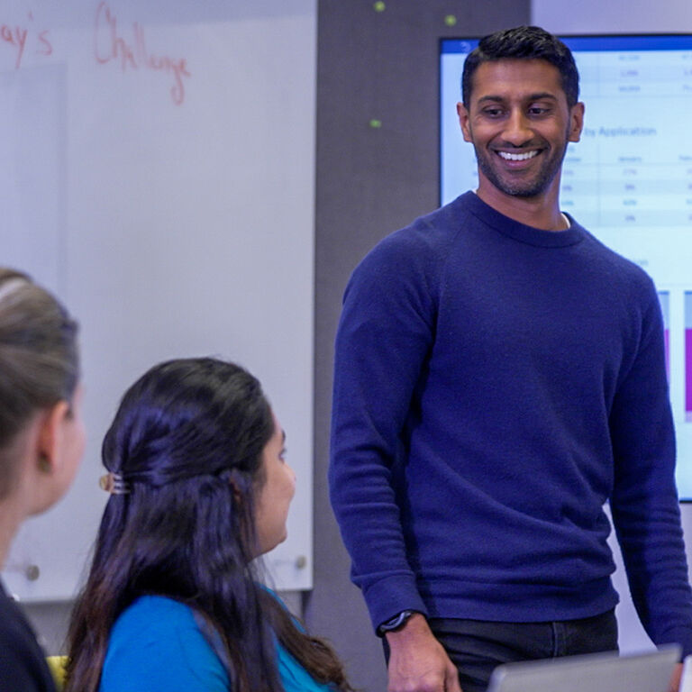 Person leading a discussion in a meeting room with presentation screen in background