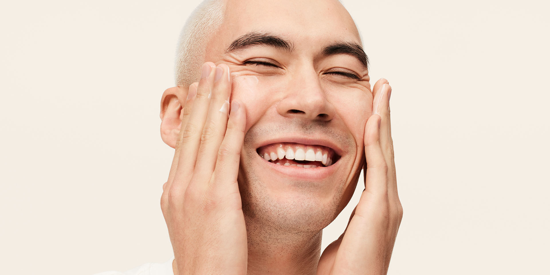 Male model applying MK Mens moisturizer to his face